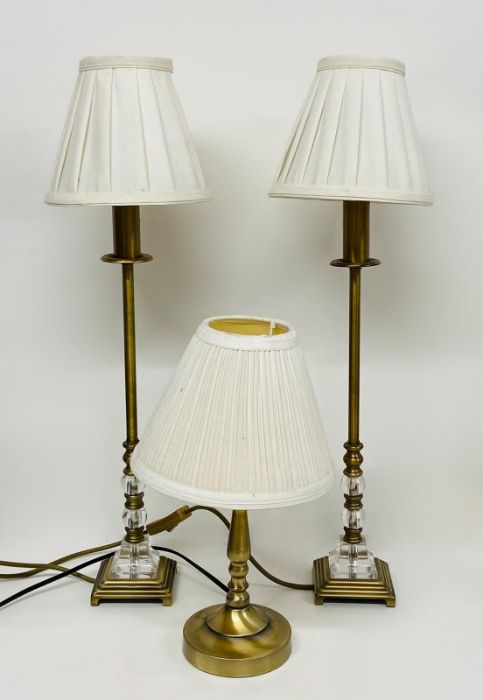 A pair of brass and glass effect lamps and one other