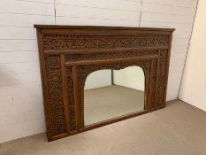 A c19th Indian Carved Teak mirror with shaped glass. The surround carved with flowers, leaves, stems