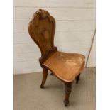 A carved wooden hall chair with shield back on turned legs
