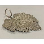 A white metal leaf with intricate design.