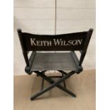 A black folding directors chair named for Keith Wilson Production Designer and Art Director (Long