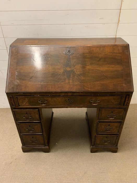 A George III mahogany bureau with sloping fall-front enclosing drawers and pigeonholes, with below 1