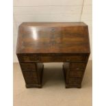 A George III mahogany bureau with sloping fall-front enclosing drawers and pigeonholes, with below 1