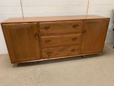 An Ercol blonde sideboard with cupboards to side and drawers to centre (H66cm W156cm D42cm)