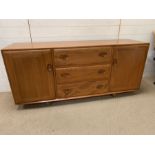 An Ercol blonde sideboard with cupboards to side and drawers to centre (H66cm W156cm D42cm)