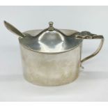 A silver mustard pot with spoon and blue glass liner. Hallmarked for London 1916.