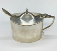 A silver mustard pot with spoon and blue glass liner. Hallmarked for London 1916.