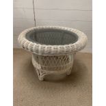 A glass topped wicker coffee table (H44cm Dia64cm)