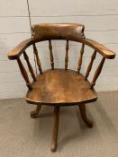 A Captains desk chair or elbow chair with spindle back and swivel base.