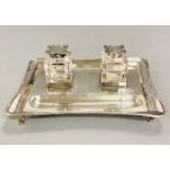 A silver desk set with glass inkwells with silver lids, dated 1909 by Charles and George Asprey (