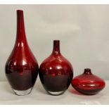 A trio of red glass vases
