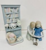 Two china ornaments, one of boy and girl sitting and reading and other of two cats and a bookcase