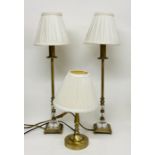 A pair of brass and glass effect lamps and one other