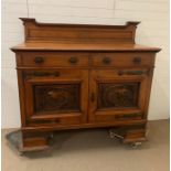 A Side cabinet with raised back, two drawers over a pair of carved doors on bracket feet. To the