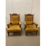 A Pair of open armchairs in gold velvet with carved backs.
