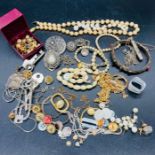 A selection of costume jewellery to include charms and pearl necklaces.