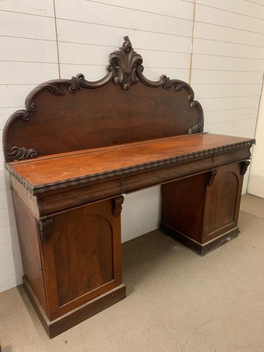 A mahogany pedestal sideboard, the raised back with scroll and foliage carving three drawers above