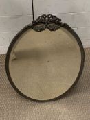 An oval mirror with ribbon top on table top stand