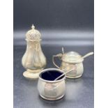 A silver mustard pot with a blue glass liner, silver salt with a blue glass liner and a silver