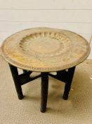 A brass tea table with carved folding legs