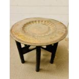 A brass tea table with carved folding legs