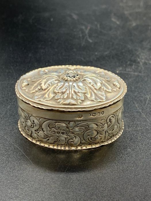 An ornate Victorian silver pill box with floral design to lid, hallmarked for Birmingham 1887