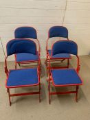 A Set of Four folding Sander metal chairs in red with blue seat pads.