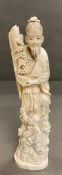 An Ivory figure of a man standing with a child at his feet.