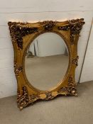 A gilt framed wall mirror with scroll details (H106cm W85cm)