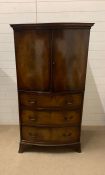A mahogany bow fronted cupboard with double doors opening to shelves and three drawers below (H153cm