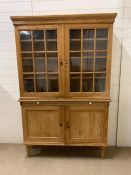 An antique pine kitchen larder with glazed panelled doors and shelf under