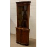 A reproduction corner cabinet with wave glass front