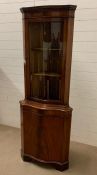 A reproduction corner cabinet with wave glass front