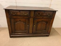 An oak side cupboard with two doors opening to a shelf and two drawers above, brass handles, panel