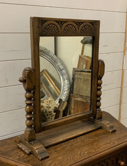 A carved table mirror on turned supports
