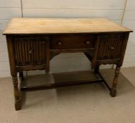 An oak dressing table with linen fold deep drawers and drawer to centre