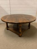 An oak circular low centre table on turned legs and shelf under (H46cm Dia106cm)