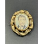 A Pinchbeck rotating brooch with portrait of a gentleman to one side and hair to the other.