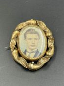 A Pinchbeck rotating brooch with portrait of a gentleman to one side and hair to the other.