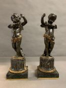 A pair of standing bronze cherubs on marble fluted pedestals with square marble and gilt bases,