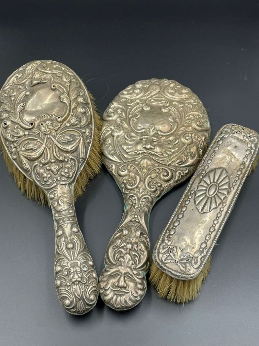 Three white metal backed dressing table brushes