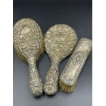 Three white metal backed dressing table brushes