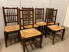 Six oak dining chairs with rush seats and turned spindles back