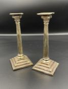 A pair of miniature Corinthian column candlesticks in white metal