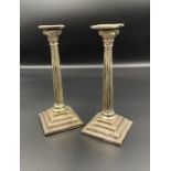 A pair of miniature Corinthian column candlesticks in white metal