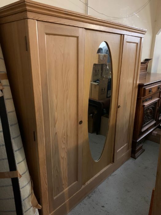 A pine triple wardrobe with hanging rails and shelves to one side (H197cm W179cm D62cm)