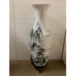 A large floor standing porcelain vase on stand with a waterfall theme white and green