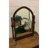 A table top mirror on turned supports and arch shaped