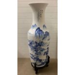 A large floor standing porcelain vase on stand with a river scene, measuring H126cm without stand