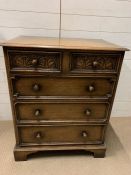 An oak panelled chest of drawers, with the top two drawers carved (H92cm W76cm D49cm)